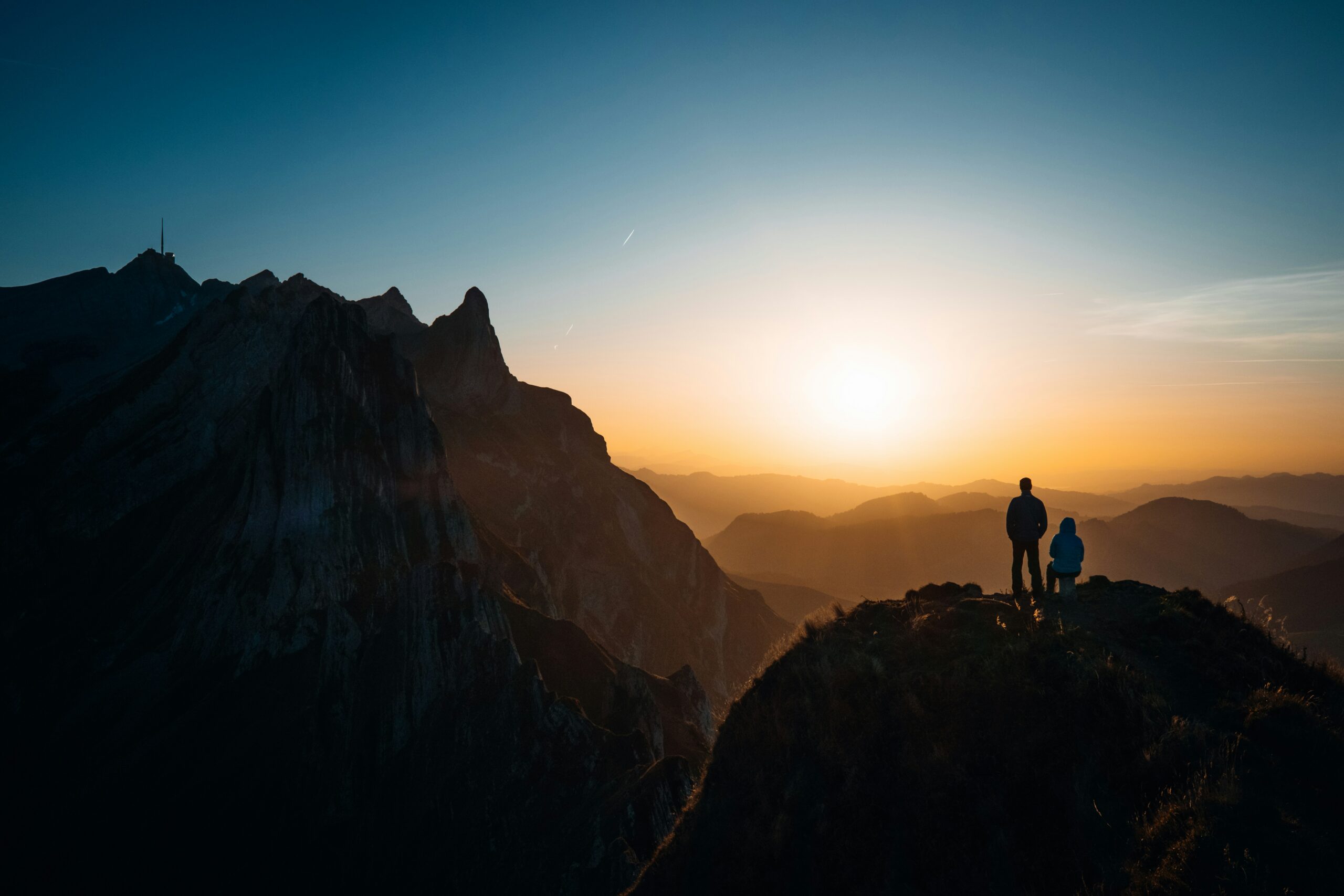 Two people looking over a mountain during sunset